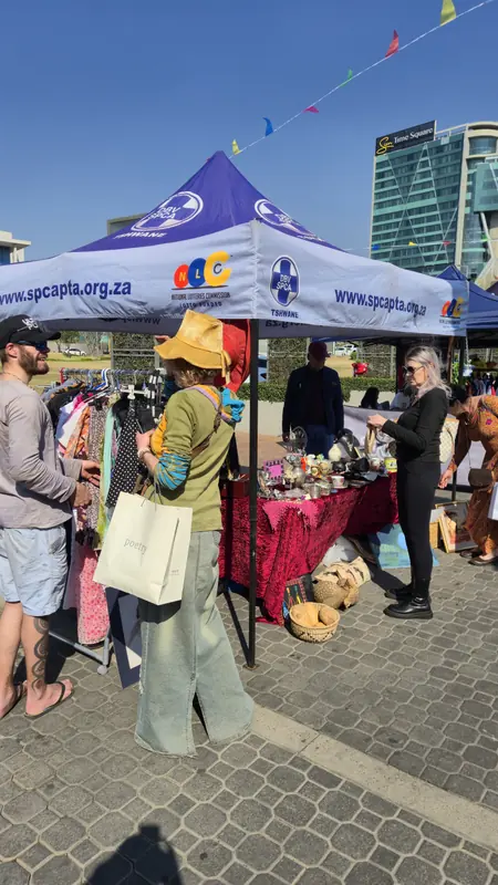 Visitors browsing clothing and collectables at a market stall