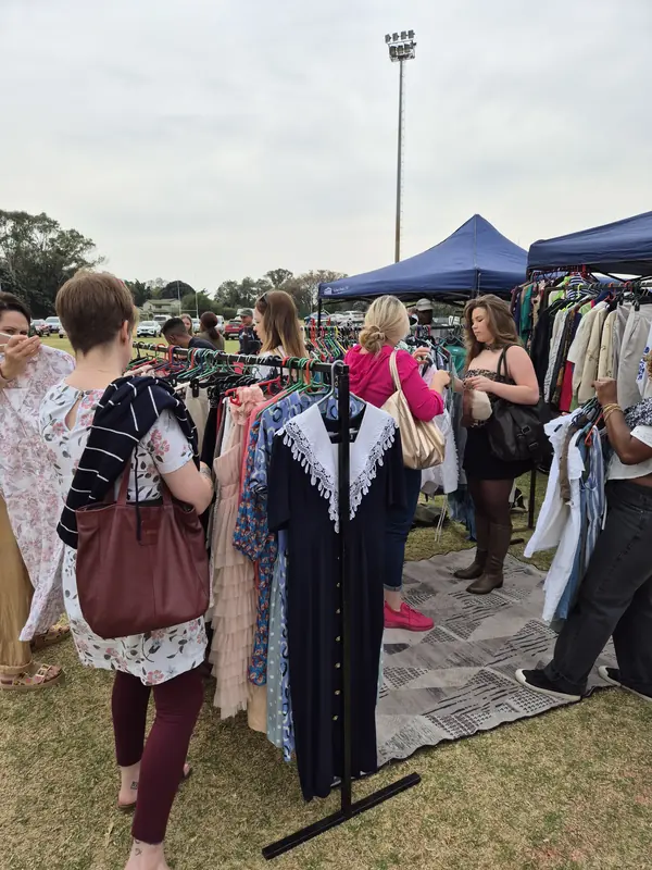 Shoppers browsing racks of vintage clothing at the market